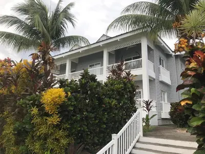 a large white house with palm trees in front of it at Pacific View Condominium in Playa Azul in Playa Azul