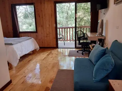 a bedroom with a bed and a couch and a balcony at Curuba Lodge in El Copey