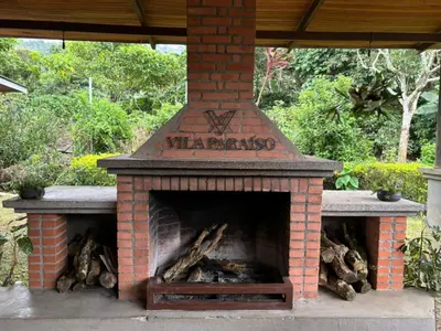 an outdoor brick fireplace with logs in it at Hotel Ribera La Paz in San Ramón