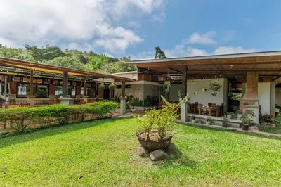 a house with a green yard in front of it at Hotel Ribera La Paz in San Ramón