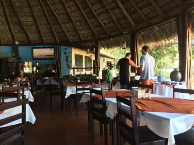 two men standing in a restaurant with tables and chairs at Best Western El Sitio Hotel in Liberia