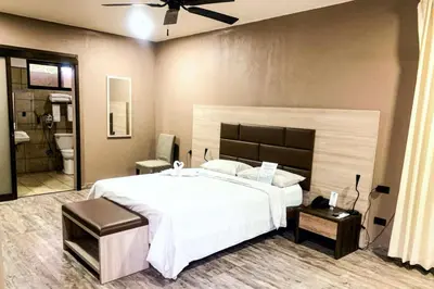 a bedroom with a large white bed and a bathroom at Best Western El Sitio Hotel in Liberia