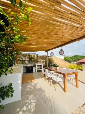 an outdoor dining area with a wooden pergola at Casa Ophelia in Tamarindo