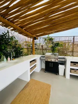 an outdoor kitchen with a wooden pergola at Casa Ophelia in Tamarindo