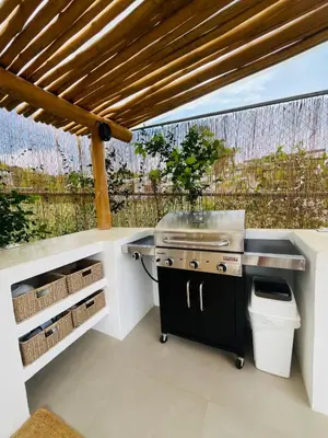 an outdoor kitchen with a grill and a table at Casa Ophelia in Tamarindo
