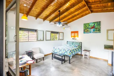 a room with a bed and a table and chairs at Macaw Villa - Riverfront With A Pool in Uvita