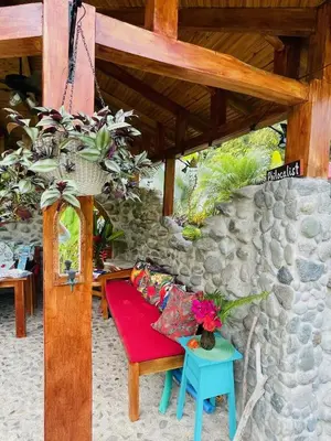 a red bench sitting under a stone wall at Macaw Villa - Riverfront With A Pool in Uvita