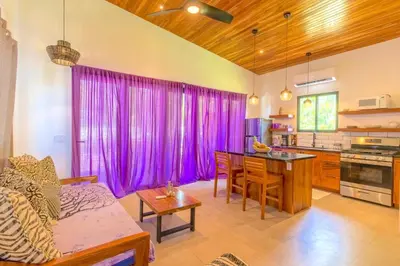 a living room with purple curtains and a kitchen at La Joya de Nosara in Playa Pelada
