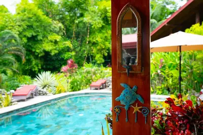 a wooden door with a sign on it next to a swimming pool at La Rana Deluxe Villa - Riverfront With A Pool in Uvita