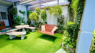 a patio with grass and a table and benches at Hostel El Pretal in Liberia