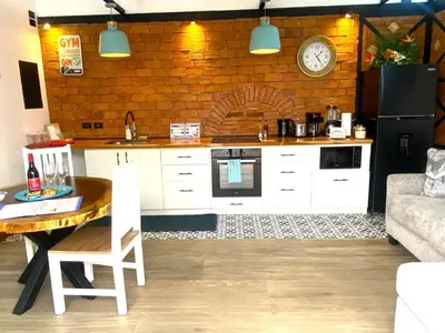 a kitchen with a table and a clock on a brick wall at Buendía Lux Piña Suite Hidden Gem Near Beach with Pool in Potrero