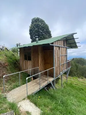 a small wooden building with a green roof on a hill at Cabaña la Chispita, Alto Jaular in Rivas