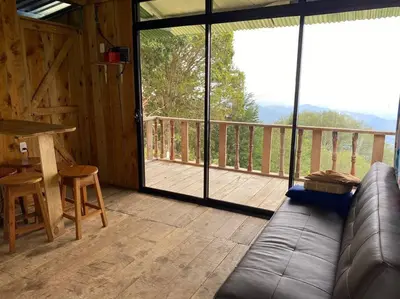 a living room with a couch and a wooden deck at Cabaña la Chispita, Alto Jaular in Rivas