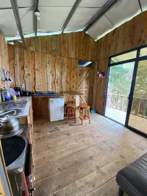 a kitchen with wooden walls and a table and a stove at Cabaña la Chispita, Alto Jaular in Rivas