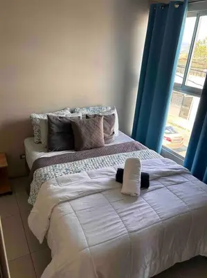 a bedroom with a bed with white sheets and a window at Casa céntrica en San Ramón in San Ramón