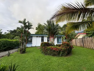 a white house with palm trees and a yard at Casa Willow Spacious and relaxing property in Ojochal