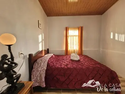 a bedroom with a red bed with a window at Vista al Volcán Tenorio y Montaña in San Rafael