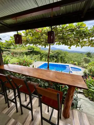a table on a porch with a view of a pool at Vista al Volcán Tenorio y Montaña in San Rafael