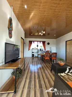 a living room with a television and a dining room at Vista al Volcán Tenorio y Montaña in San Rafael