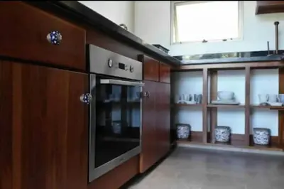 a kitchen with a stove and wooden cabinets and a window at Tortuga Premium Riverfront Jungle Villa with Jacuzzi and Pool in Uvita