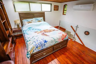 a bedroom with a bed with a wooden floor at Tortuga Premium Riverfront Jungle Villa with Jacuzzi and Pool in Uvita