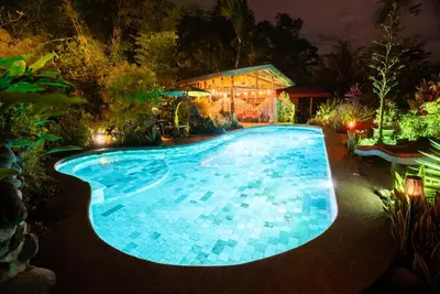 a swimming pool at night with a house at Sloth Premium Riverfront Jungle Villa with Jacuzzi and Pool in Uvita