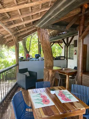 a porch with a table and chairs and a tree at Quinta Esencia in Brasilito