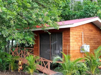 a small wooden cabin with a balcony and trees at Cabañas Del Lago . Bungalows in San Ramón