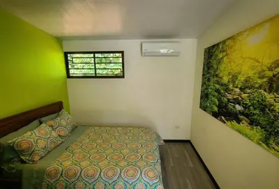 a bedroom with a bed and a painting on the wall at Pura Vida - Villa Elenita in Parrita