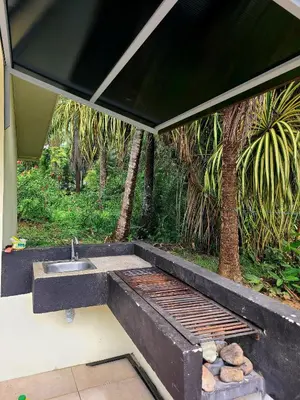 a barbecue with a sink and a grill with rocks at Pura Vida - Villa Elenita in Parrita