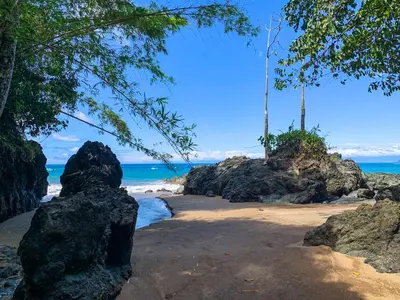 a beach with some rocks and the ocean at Las Caletas Lodge in Drake