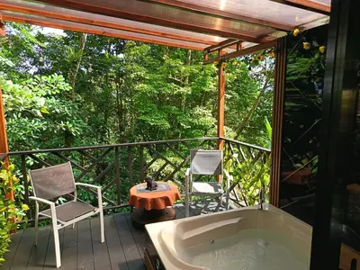 a tub on a deck with two chairs and a table at Breezes Ecolodge in San Ramón