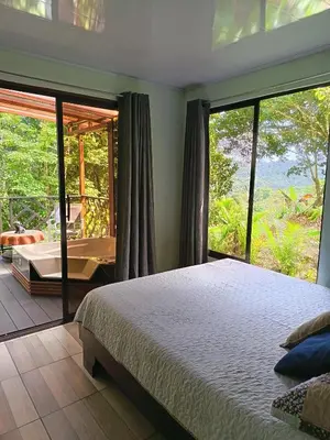 a bedroom with a bed and a large window at Breezes Ecolodge in San Ramón