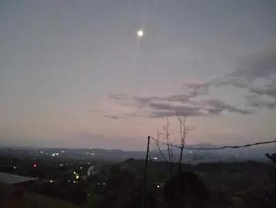 a moon in the sky over a city at night at Breezes Ecolodge in San Ramón