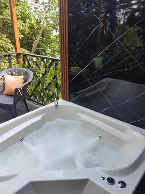 a bath tub filled with water next to a balcony at Breezes Ecolodge in San Ramón