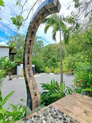 a brick archway in a garden with a palm tree at Casa Namaste del Pacifico - Luxury Villa in Santa Teresa Beach