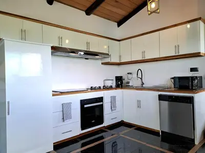 a kitchen with white cabinets and a black dishwasher at Casa Namaste del Pacifico - Luxury Villa in Santa Teresa Beach