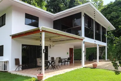 a large white house with a deck and patio at Casa Garrobo in Dominical