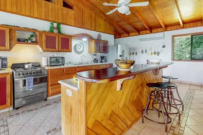 a kitchen with wooden cabinets and a wooden counter top at Casa Garrobo in Dominical