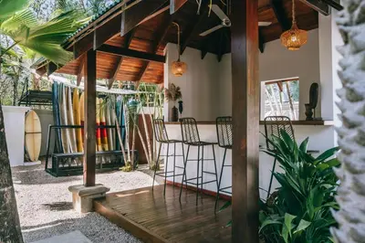 a porch with chairs and a table with a surfboard at Dream Surf House Avellana in Playa Avellana