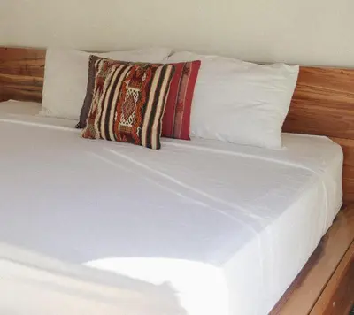 a bed with white sheets and a pillow on it at Dream Surf House Avellana in Playa Avellana