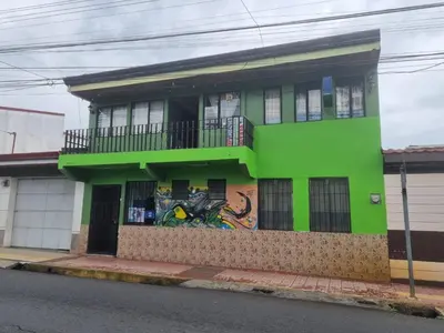 a green building with graffiti on the side of it at Hotel Paradise Alajuela in Alajuela City