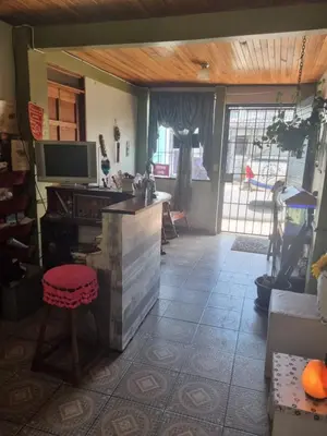a room with a kitchen with a tv and a stool at Hotel Paradise Alajuela in Alajuela City