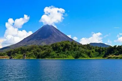 a mountain with smoke coming out of it next to a lake at Villa Aurora with Jacuzzi in La Fortuna in Fortuna