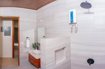 a bathroom with a toilet and a tv on the wall at Villa Aurora with Jacuzzi in La Fortuna in Fortuna