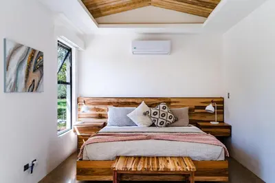 a bedroom with a large bed with a wooden headboard at Casa Cenizaro- 4Br House In Hacienda Pinilla in Tamarindo