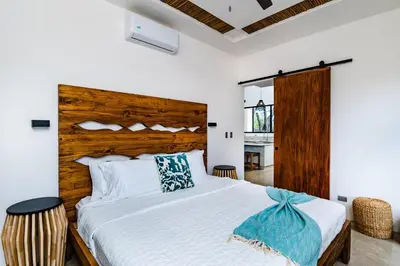 a bedroom with a large bed with a wooden headboard at Casa Cenizaro- 4Br House In Hacienda Pinilla in Tamarindo