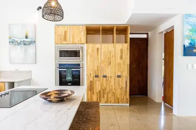 a kitchen with wooden cabinets and a bowl on a counter at Casa Cenizaro- 4Br House In Hacienda Pinilla in Tamarindo