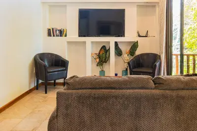 a living room with a couch and two chairs and a tv at Surfside Apartments - Mal Pais in Mal País
