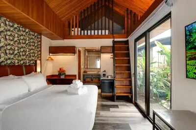 a bedroom in a villa with a bed and a kitchen at Suwa Villa Arenal in Fortuna